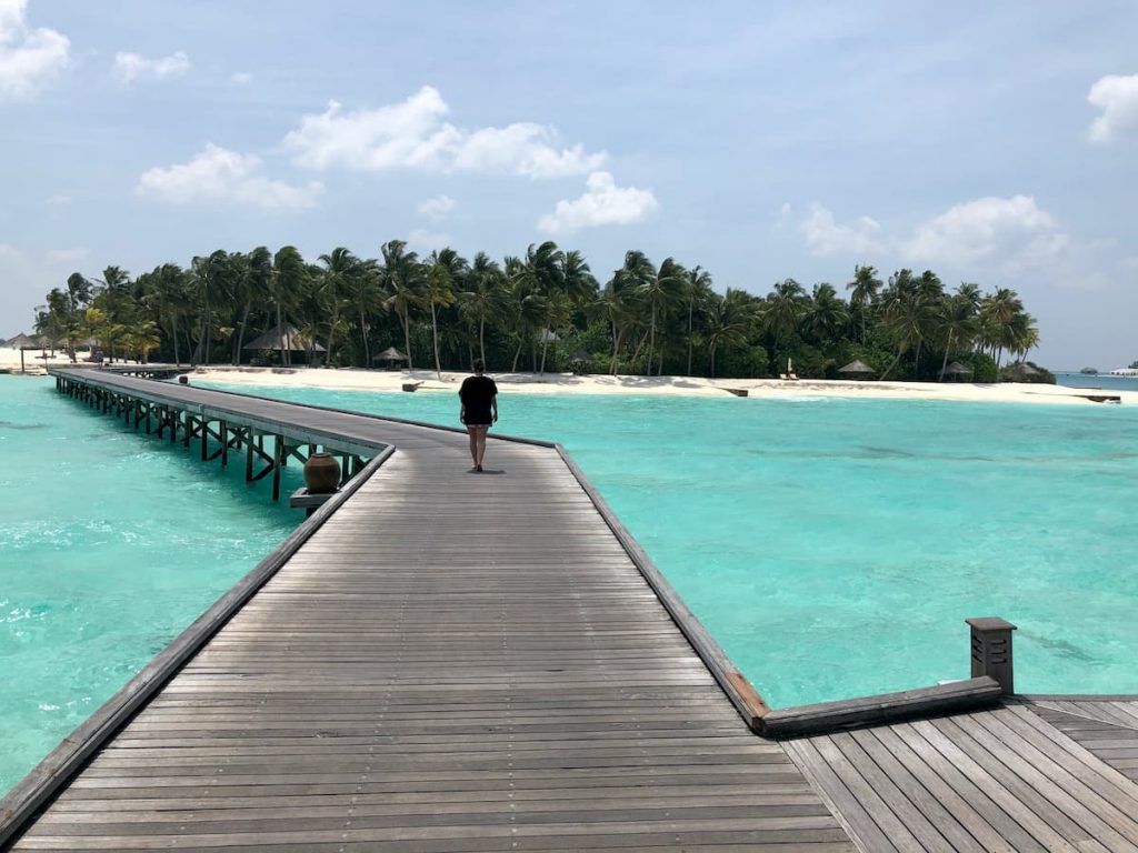 spa-maldives-woman-walking-walkway-ocean